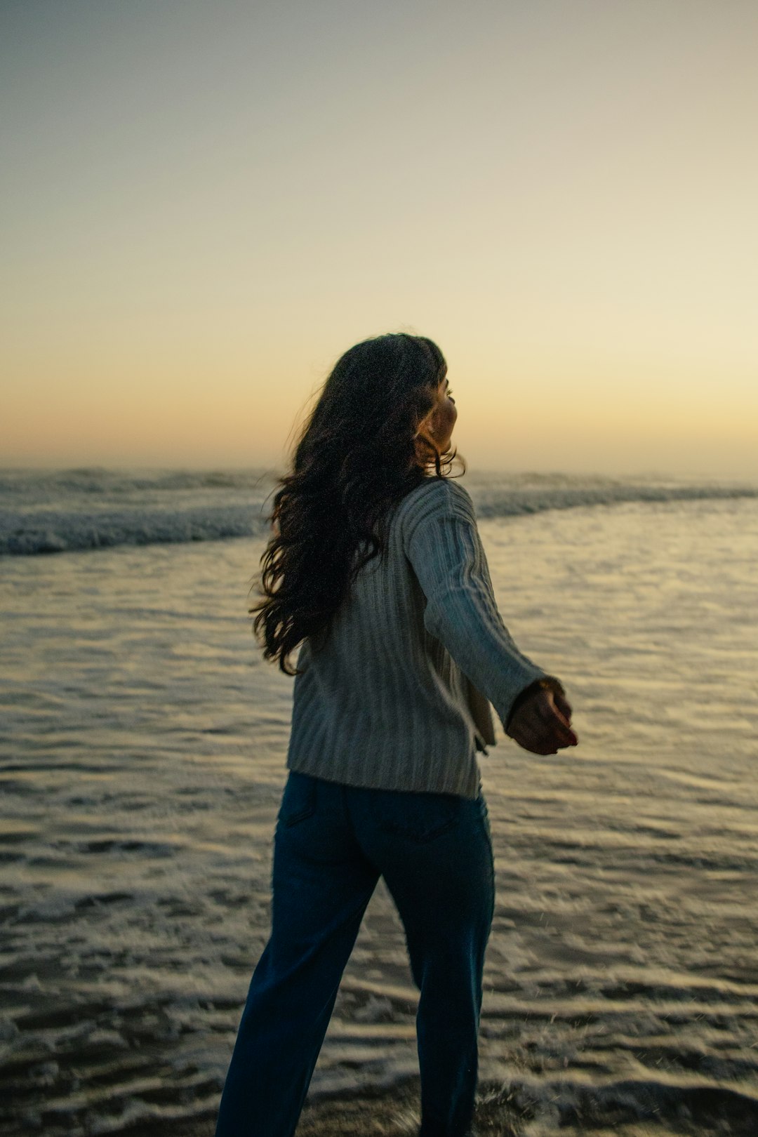 Woman standing in the ocean at sunset